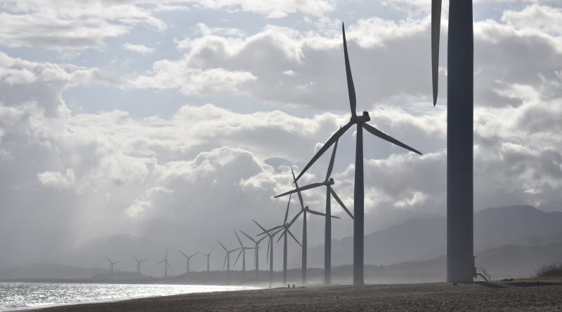 A line of wind turbines on the beach next to sea