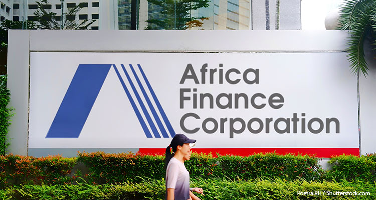 A woman is walking past an Africa Finance Corporation sign.