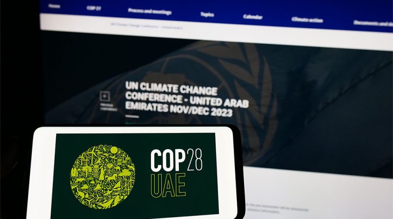 Image of a mobile phone with the COP 28 logo on the screen, in front of a monitor displaying the same website to support cop28 article