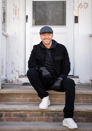 Donnie Wahlberg  sitting on steps in front of a white door