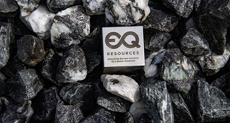 EQResources logo on a tungsten block amongst rocks