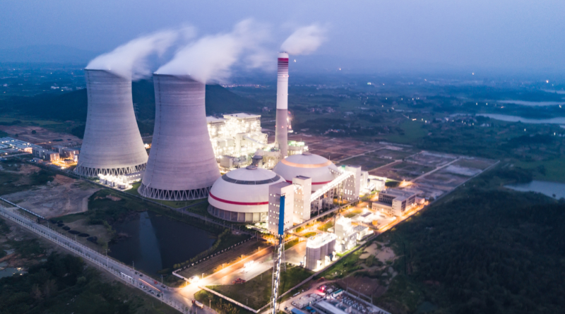 Aerial view of a nuclear power plant at dusk with illuminated cooling towers and surrounding facilities, symbolizing the operations of leading nuclear power companies.