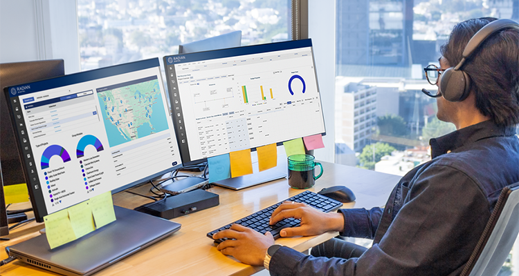 Office worker looking at graphs on computer screens