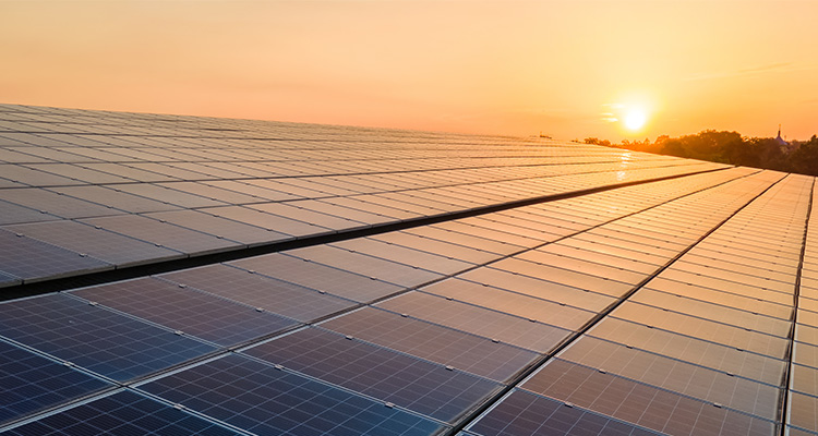Blue photovoltaic solar panels mounted on building roof for producing clean ecological electricity at sunset. Production of renewable energy concept.
