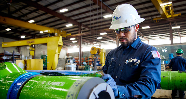 BICO Drilling Tools’ reputation is built on performance, industry experience, and top-notch customer service worker performing quality control or maintenance on a large, green cylindrical component