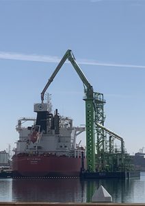 bulk carrier ship being loaded or unloaded by a harbor mobile crane