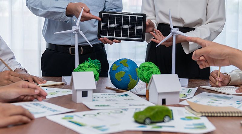 4 of the Best Renewable Energy Plans for Businesses Business professionals gathered round desk discussing renewable energy plans