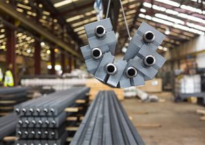 a permanent magnetic lifter being used to move steel rods in a warehouse or factory