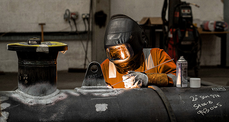 a welder working on a large pipe