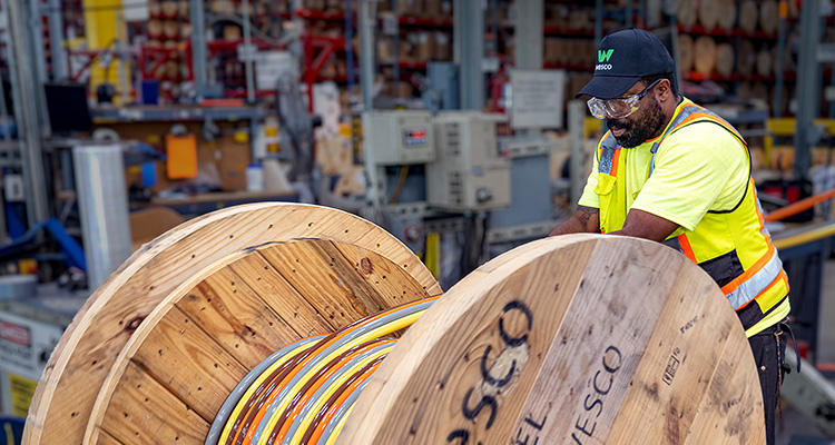 a man working in a warehouse with large wooden reels of cable