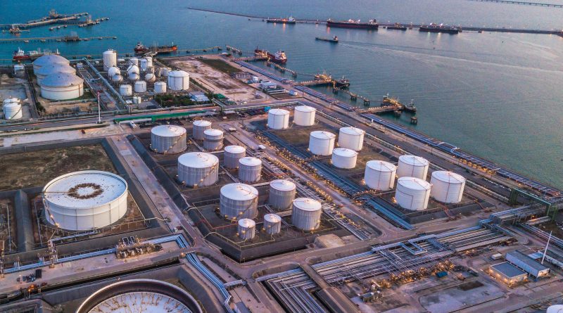 Oil storage tanks at an industrial refinery during a period of tightening global crude inventories.