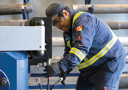 an industrial technician or machinist working on heavy downhole drilling machinery within an oil and gas equipment facility