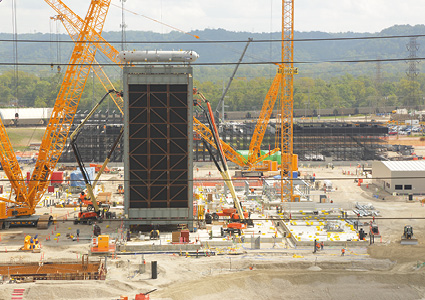 a Heat Recovery Steam Generator (HRSG) module being erected by heavy-lift crawler cranes at a power plant construction site.