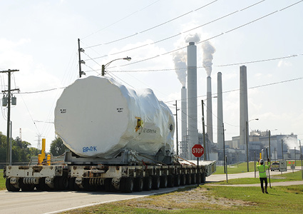 a heavy industrial transport operation moving a massive piece of machinery down a public road