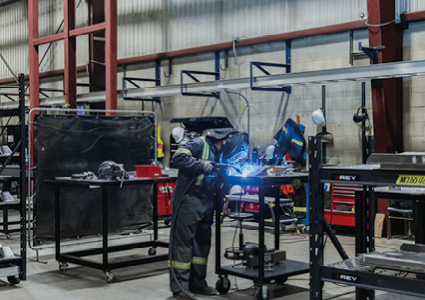 a worker performing metal fabrication and welding in an industrial setting