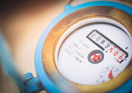  a close-up, angled view of a standard mechanical water meter encased in a blue plastic or painted metal body