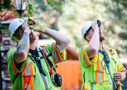 utility workers using specialized equipment to perform inspections while wearing high-visibility safety vests and hard hats