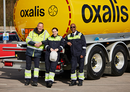 a group of transport personnel standing in front of a yellow tanker truck
