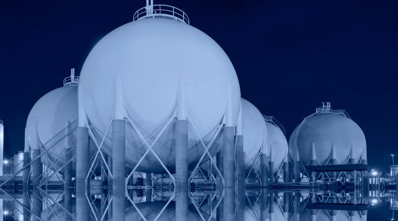 Liquefied natural gas storage tanks and industrial infrastructure in the background.