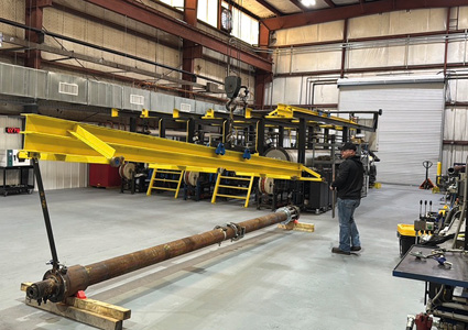  large industrial workshop or fabrication facility featuring a long metal cylinder or shaft resting on support blocks