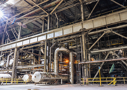 an industrial plant featuring steel structural framing, large-scale metal piping networks, and cylindrical storage tanks