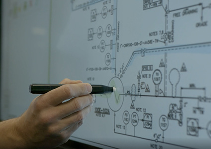 a person using a pen to point at or mark up an engineering diagram