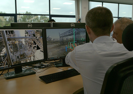 engineers or technicians working at dual-computer workstations, viewing 3D digital models