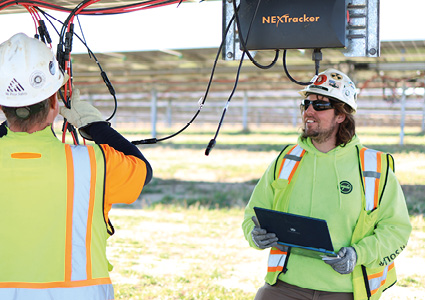 solar field technicians working on a utility-scale solar tracker system featuring a NEXTracker controller unit
