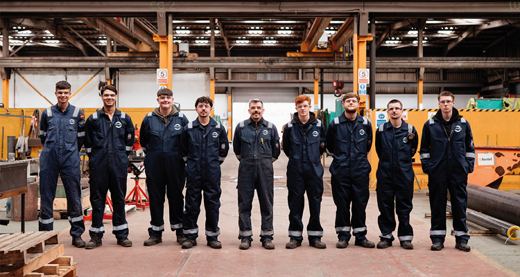 a group of engineering apprentices or trainees standing in a workshop
